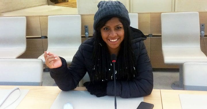 Tjej som sitter vid ett bord med en mikrofon framför sig.