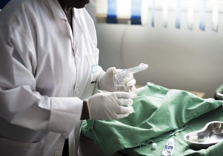 Sjukhusmiljö, man ser en person i vit rock som håller i en spruta.