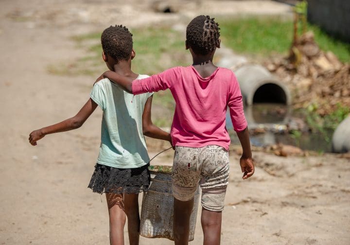 Två tjejer går med en cykel.