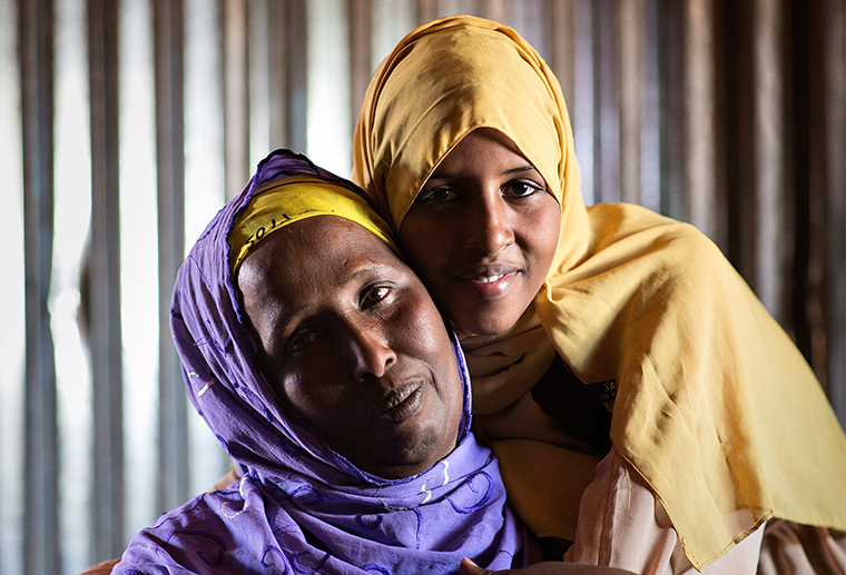 Två kvinnor med huvudslöjor tittar in i kameran.