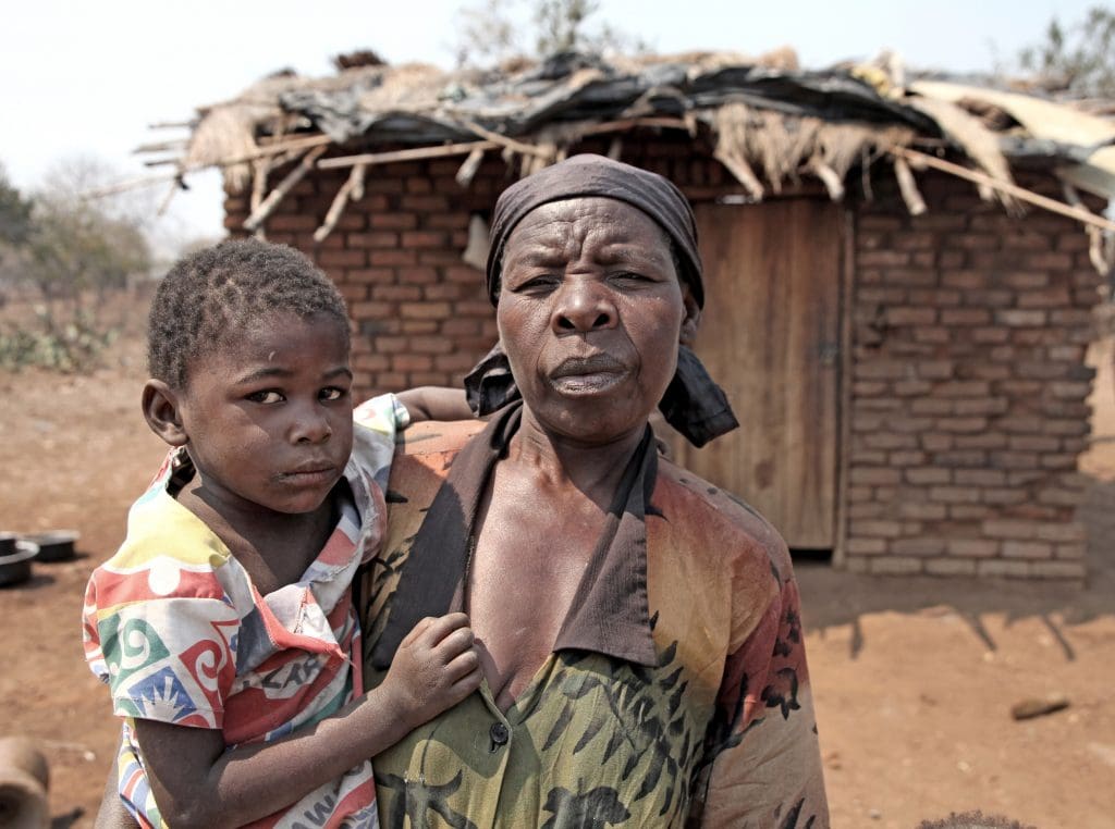 Kvinna och barn framför ett hus.