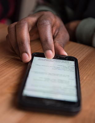 närbild på en hand som pekar på en mobilskärm.