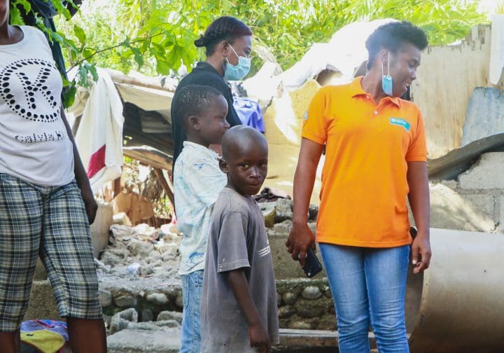 Barn och vuxna på Haiti förstörd förstörd byggnad.