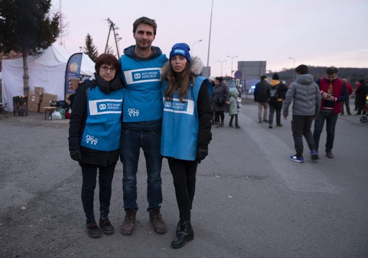 Tre personer i blåa västar med SOS Barnbyars logga på.