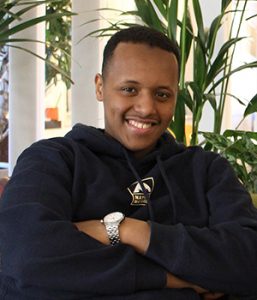 Ung man i hoodie ler varmt mot kameran.