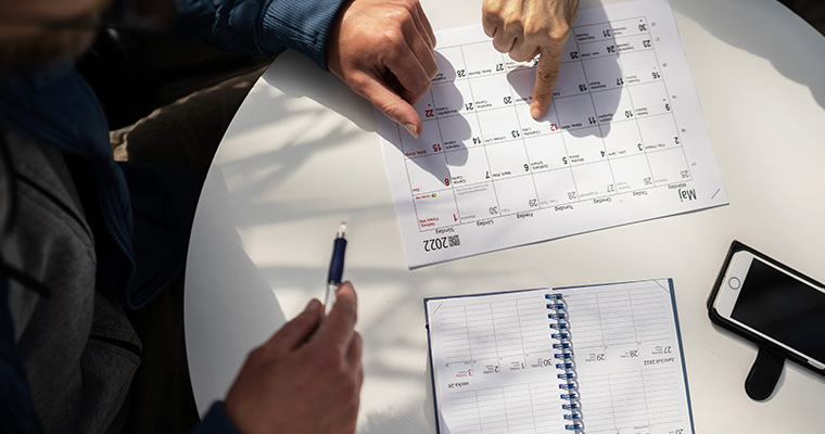 Ett bord med en kalender. En hand pekar på datum i kalendern.