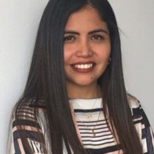 kvinna med långt svart hår och randig tröja ler