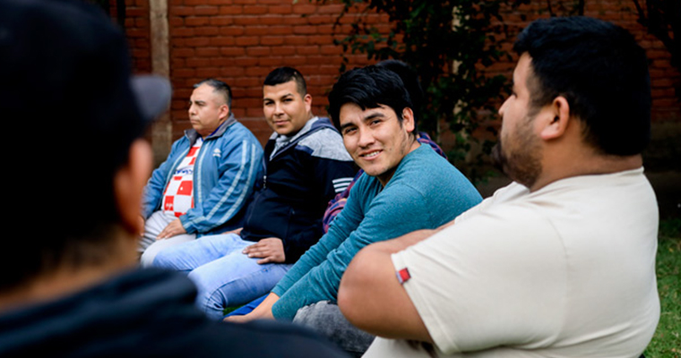 män sitter på stolar utomhus och pratar