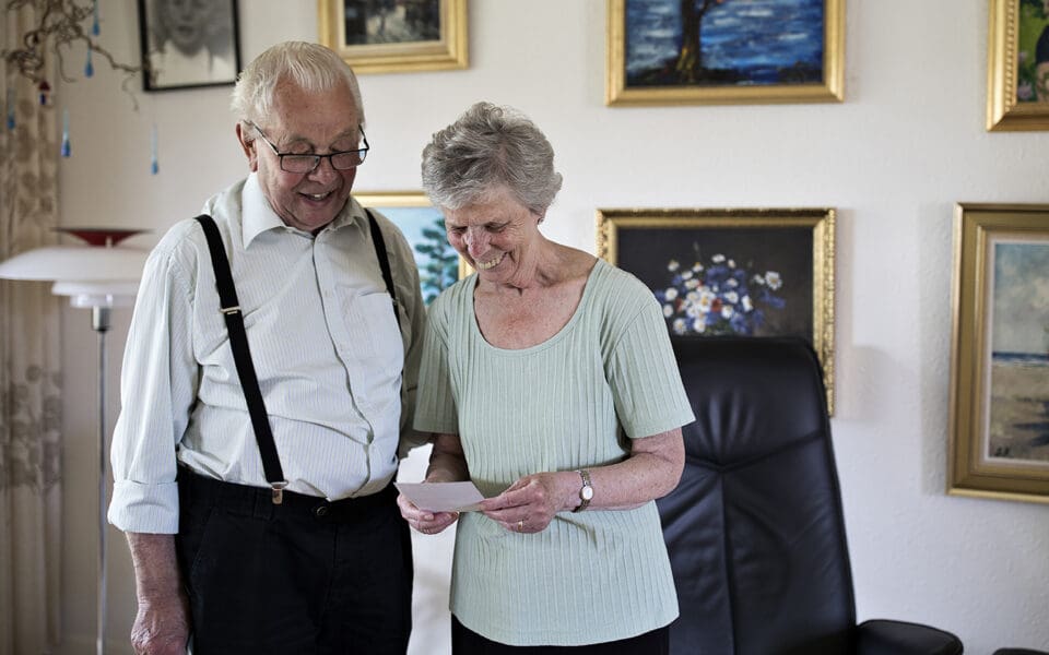 En man och en kvinna som tittar på ett foto. De står framför en tavelvägg.