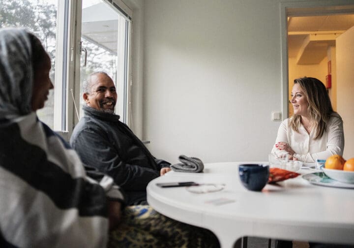 Familj som får stöd av SOS Barnbyars program sitter vid ett runt bord.