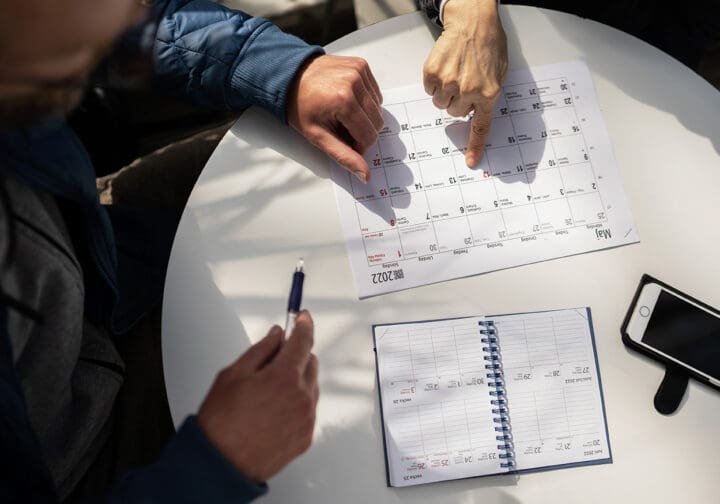 Ett bord med en kalender. En hand pekar på datum i kalendern.