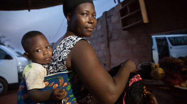 Mamma med ett barn i bärsele på ryggen