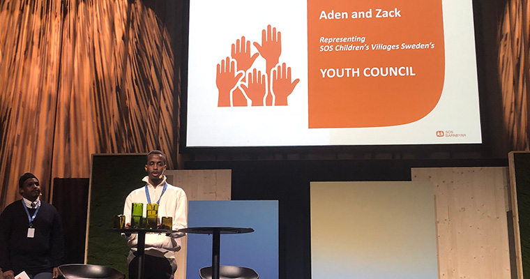 Två ungdomar står på en scen och presenterar