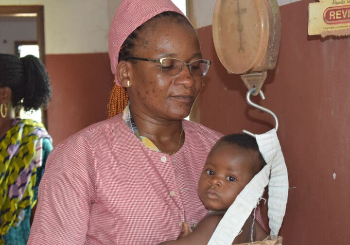 Barnmorska och en bebis som blir vägd.