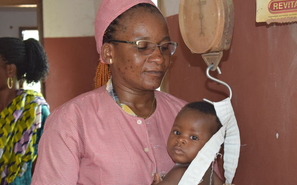 Barnmorska och en bebis som blir vägd.