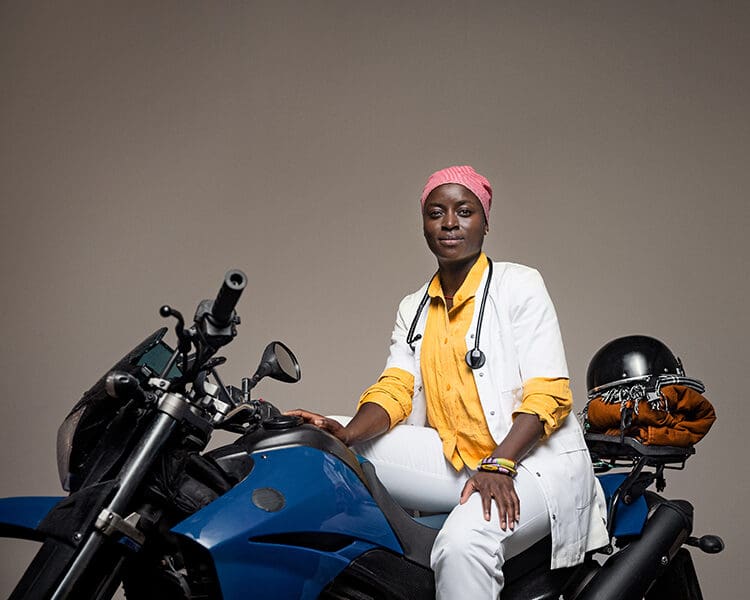 Kvinna i sjukvårdsuniform som sitter på en motorcykel.