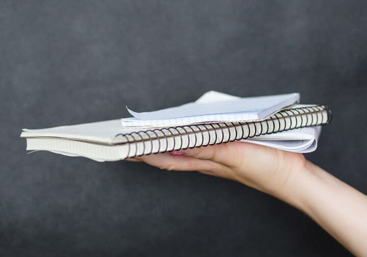 En utsträckt hand som håller i två skrivblock.