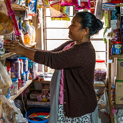Kvinna mörk kofta i butik ställer upp varor på hyllorna