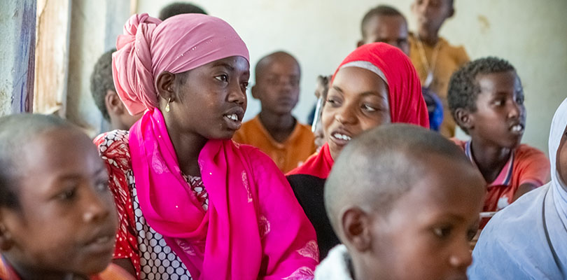 Flicka i rosa kläder i klassrum pratar med kompisar