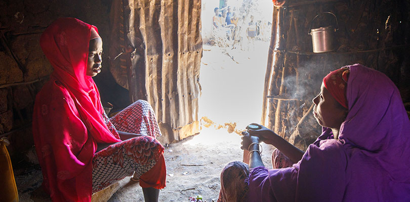ETt barn och en kvinna sitter innanför ingången till ett tält