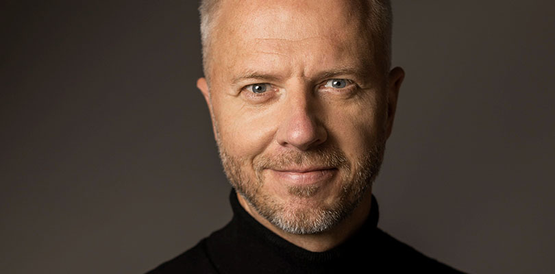 Man i svart polo ler