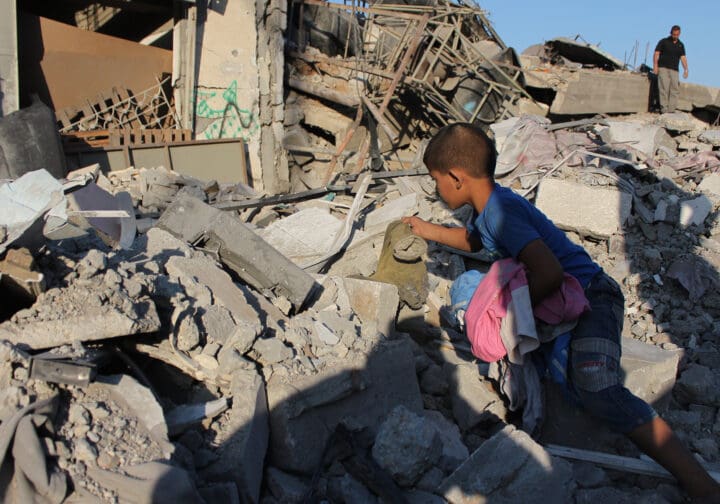 Barn i Gaza vid en förstörd byggnad.