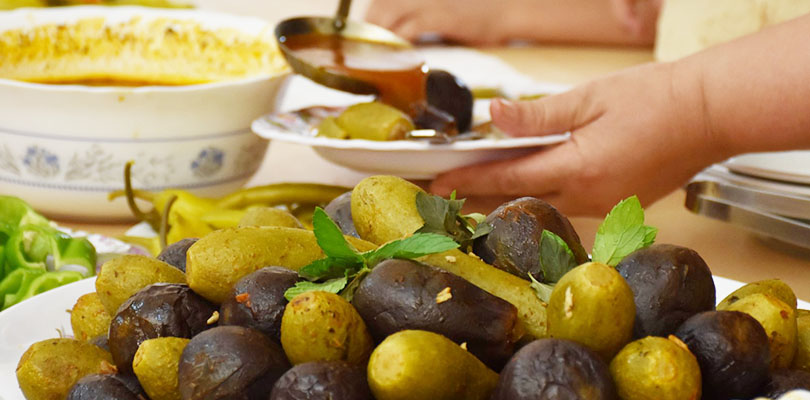 Fyllda aubergines på ett fat och en hand som häller upp tomatbuljong på en tallrik