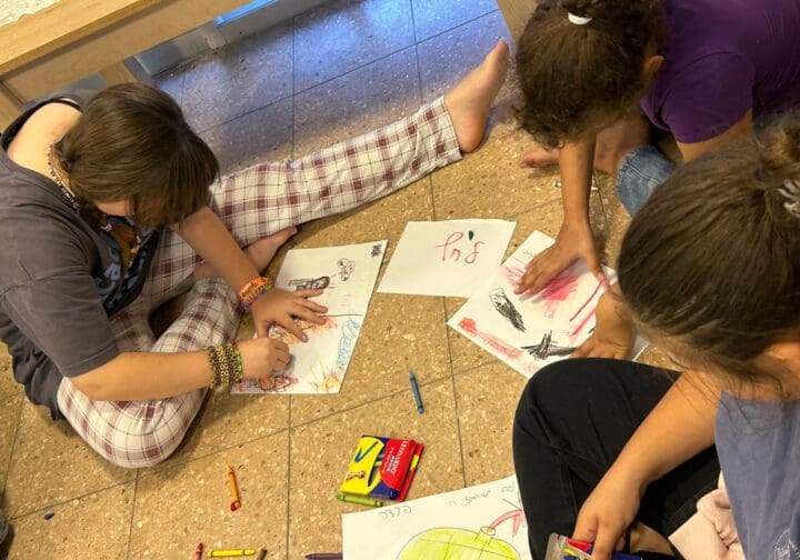 Barn som sitter på golvet och ritar.