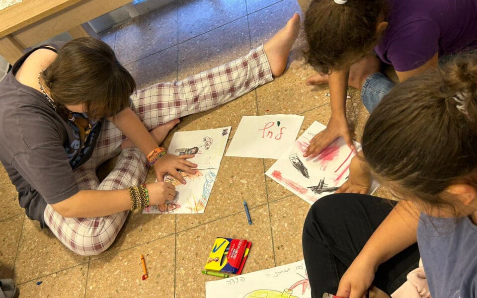 Barn som sitter på golvet och ritar.