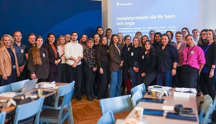 Ett tjugotal människor står på rad i en föreläsningssal