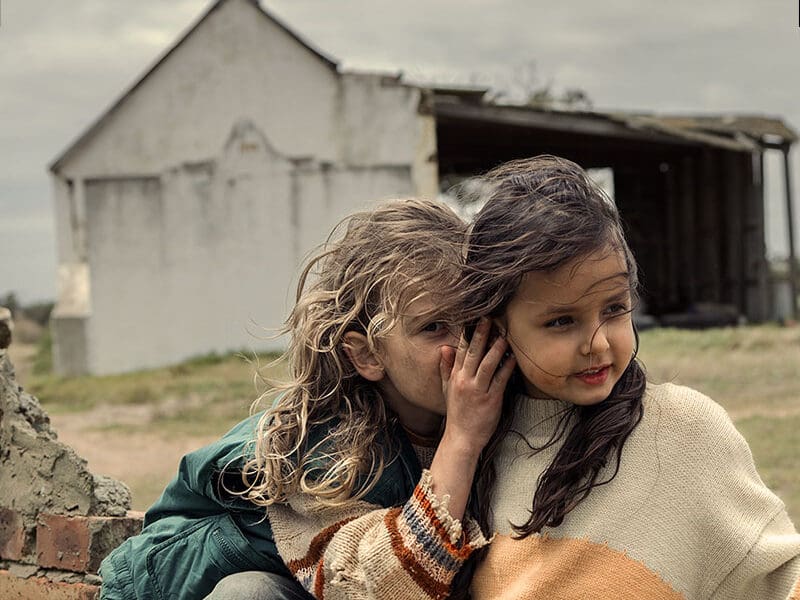 Två flickor som viskar och ser glada ut.