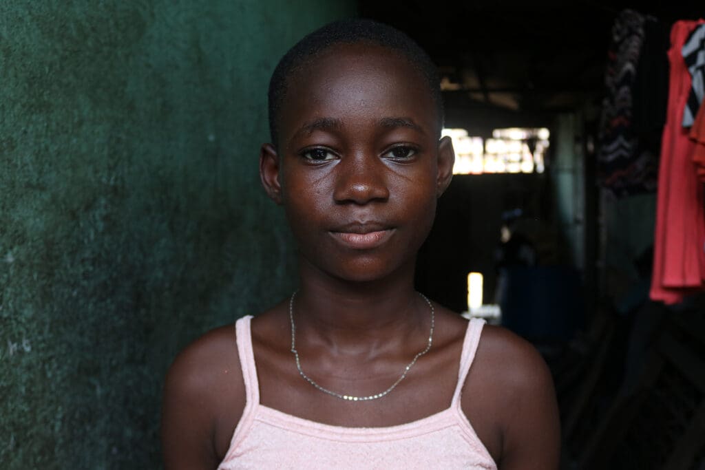 Allvarlig flicka i rosa linne tittar rakt fram.