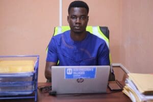 Klaus Quansa, har mørkt kort hår og blå t-skjorte og sitter foran PCen ved en skrivepult. 