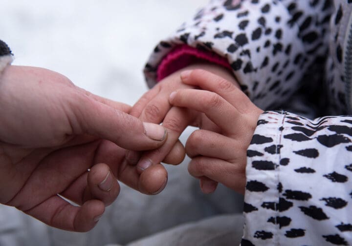 Barnhand som håller i en vuxens hand.
