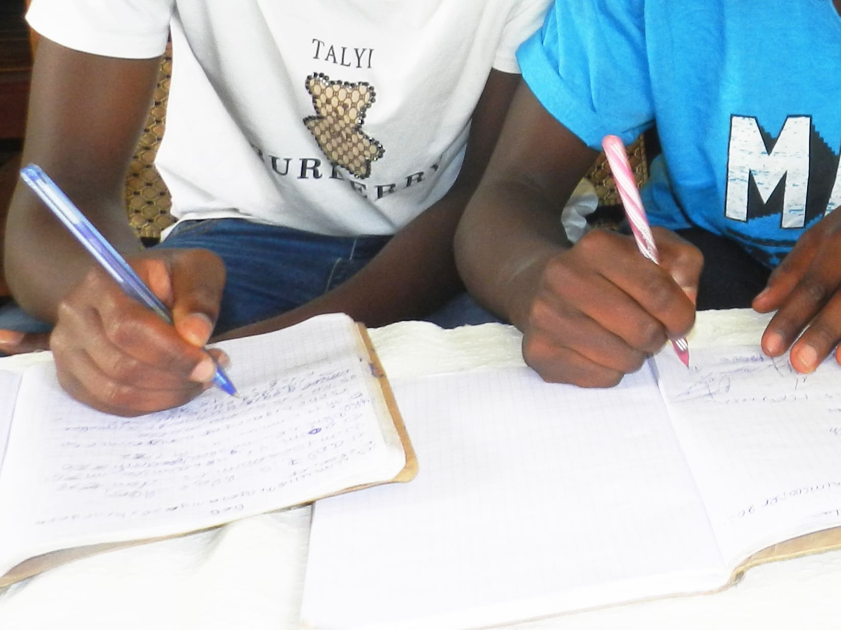 Barnhänder som skriver i varsin bok-