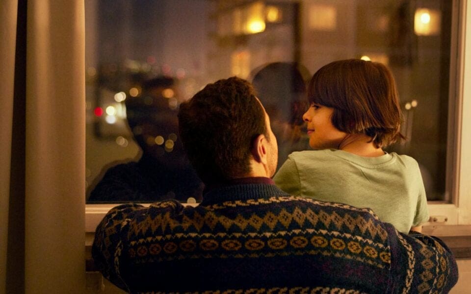 Pappa och son som tittar ut genom ett fönster.