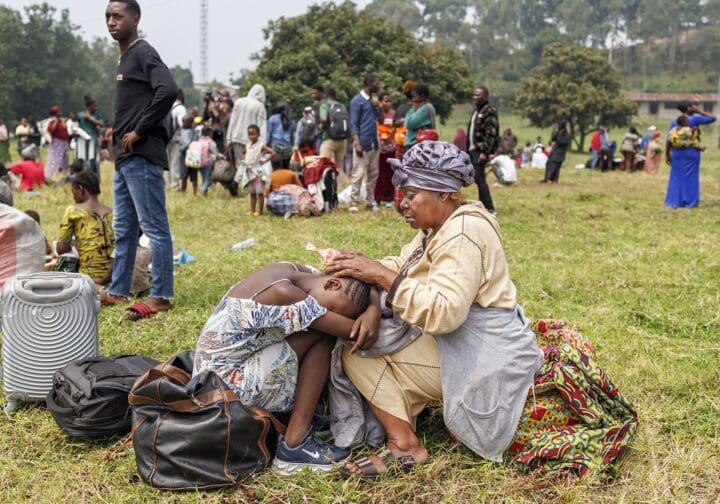 Kvinna och barn som sitter på en gräsmatta med packning.