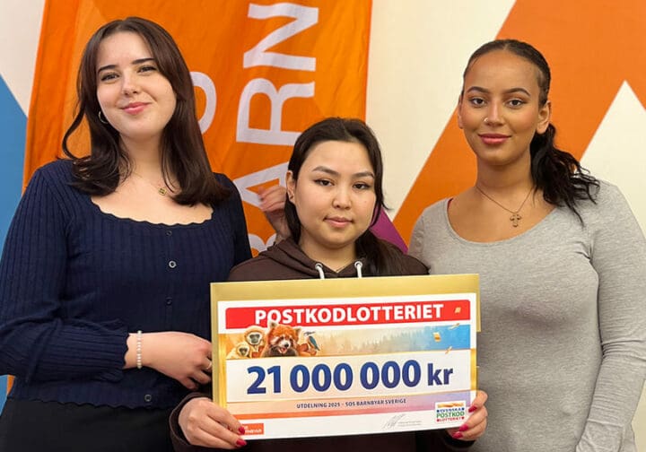 Tre unga tjejer håller i en stor check