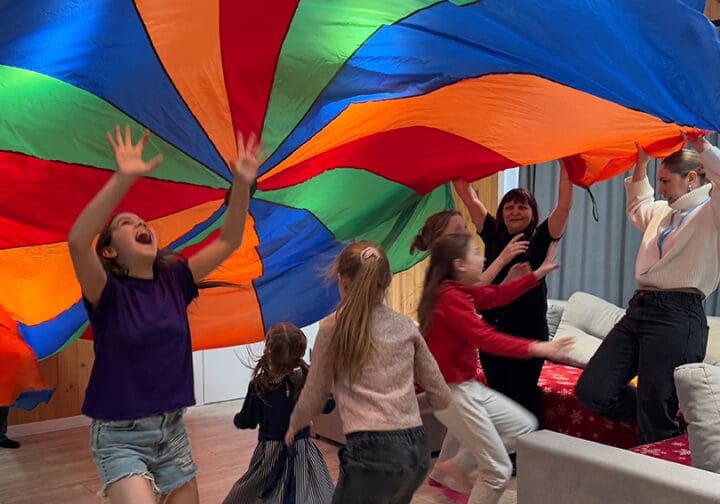 Barn lekar under ett färggrant tygstycke