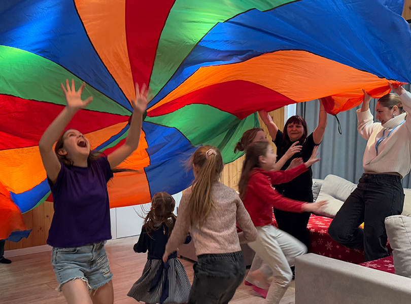 Barn lekar under ett färggrant tygstycke