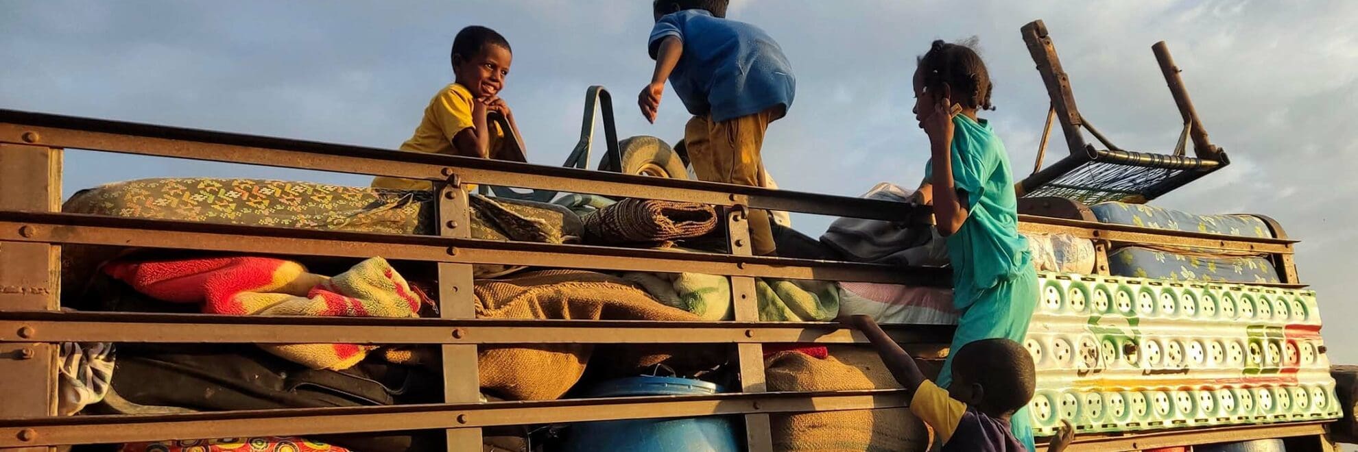 Barn från Sudan på flykt, de leker på ett flak fyllt med möbler och packning.