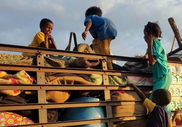 Barn från Sudan på flykt, de leker på ett flak fyllt med möbler och packning.