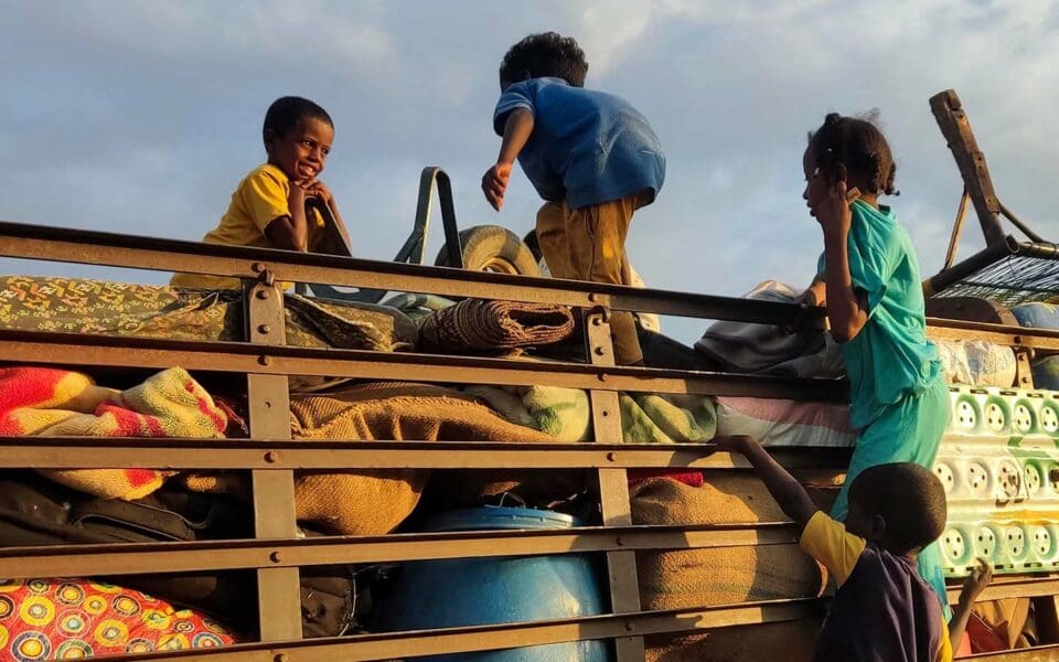 Barn från Sudan på flykt, de leker på ett flak fyllt med möbler och packning.